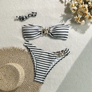Detailed flat lay of striped bikini set featuring gold starfish metal buckles on beige mat