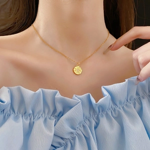 Gros plan d'un collier doré avec pendentif étoile boussole porté par un mannequin chic