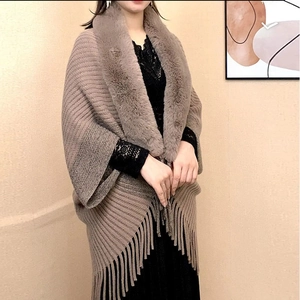 Detailed close-up of knit shawl with thick faux fur collar and elegant tassel hem finish