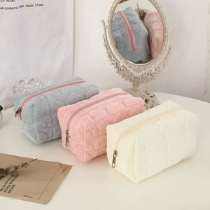 Three-piece cream cloud plush makeup bags with heart quilting in blue, pink, and beige