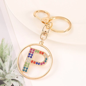 Detail of gold letter P keychain with colorful rhinestones on white plate background