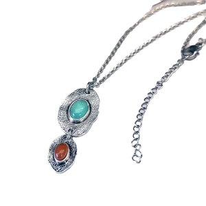 Bohemian double pendant necklace with turquoise and reddish-brown stones on white background