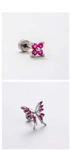 Macro detail of clover and butterfly ear studs with rose red zircon stones on silver steel