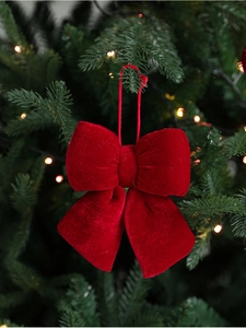 Close-up of a deep red velvet Christmas bow hanging on a decorated Christmas tree