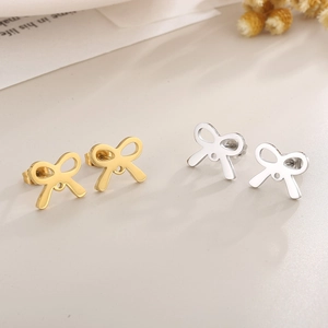 Detailed view of hollow bow-shaped stud earrings in gold and silver polished steel