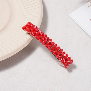 Détail d'une barrette à perles de cristal rouge sur une assiette en céramique