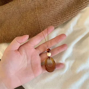 Détail du pendentif fleur vintage avec perles en bois et pompon sur collier ethnique