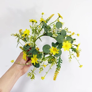Detail of a candle ring wreath featuring yellow daisies and green eucalyptus leaves