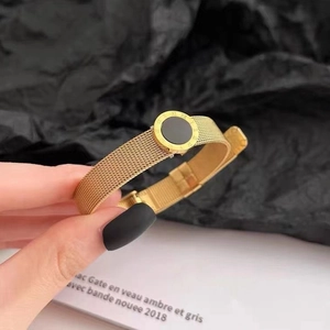 Goldenes Mesh-Armband mit römischen Ziffern und schwarzem Charme an der Hand