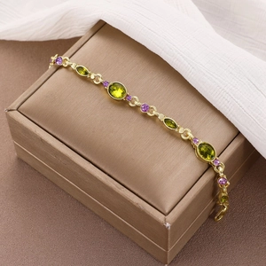 Bracciale vintage doppio strato dorato con gemme verdi e viola su scatola di gioielli