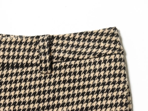 Detail view of yellow houndstooth cargo pants featuring waist loops and wool texture