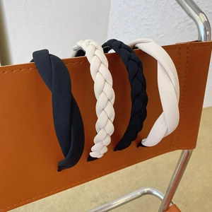 Braided black and white sponge padded headbands displayed on a modern leather chair