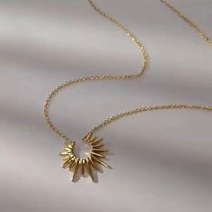 Detailed close-up of golden sunburst pendant on a fine cross chain necklace