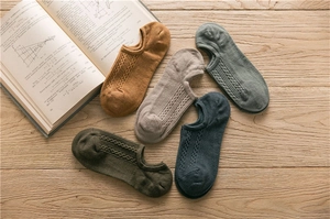 Detail von fünf Paar Baumwollsocken für Herren mit Zopfmuster auf hellem Holzuntergrund