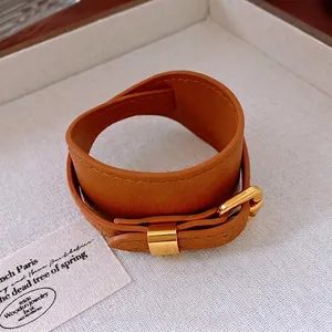 Vintage brown double-wrap faux leather choker with gold buckle on textured tray