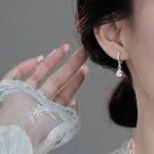 Close-up of S925 silver hoop earrings with pear-cut crystal pendant on a model