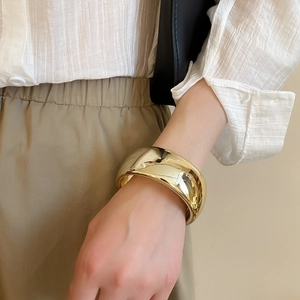 Polished wide gold cuff bracelet on model's wrist with casual chic styling
