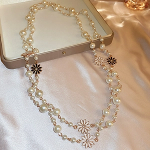 Detail of double-layer necklace with white pearls and daisies on silk fabric