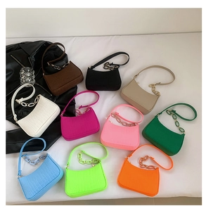 Flat lay of crocodile pattern underarm bags in ten vibrant colors with resin chains
