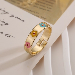 Detail of gold MAMA ring featuring colorful enamel flowers on an open band