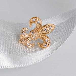 Golden Fleur-de-lis brooch with crystal rhinestones on a white textured ribbon background