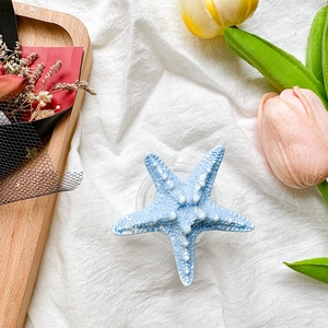 Detail view of a sky blue starfish-shaped grip on a textured white fabric background