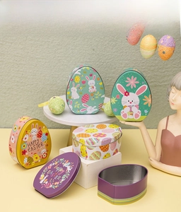 Flat Easter egg-shaped tin boxes with rabbit prints displayed on a decorative stand