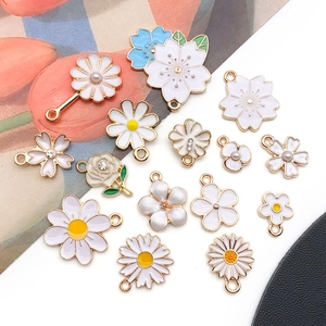 Close-up of assorted white enamel flower charms with gold edges for DIY jewelry making