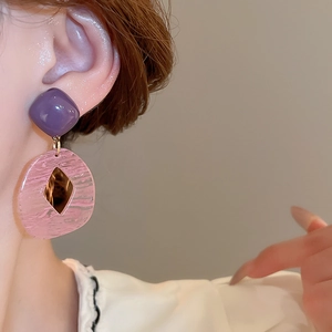 Close-up of resin geometric earrings with purple square and pink circular pendant
