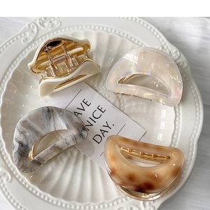 Close-up of four leopard acetate hair claws in cream, pearl, and marble on a white plate