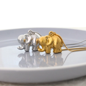 Macro shot of gold and silver elephant pendants on polished snakeskin chains