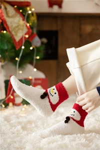 Detail of red and white coral fleece Christmas snowman socks worn in a festive cozy setting