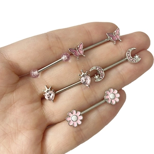 Vue détaillée de quatre piercings de mamelon en acier avec papillon rose et cœurs