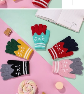 Flat lay of five pairs of colorful knitted kids gloves with cute cat patterns and stripes