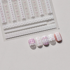 Detail of white and pink lace bow embossed nail art stickers with 3D texture and finish