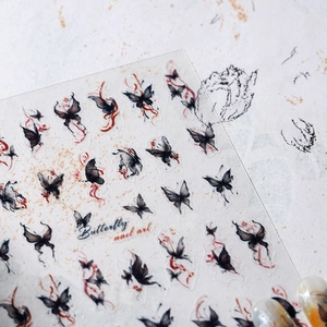 Macro shot of black butterfly nail stickers with red details and floral patterns