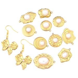 Macro shot of gold stainless steel sunflower charms and pearl butterfly earrings detail