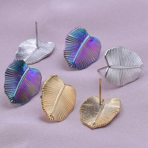 Dettaglio macro di orecchini a foglia in acciaio inossidabile argento, oro e arcobaleno