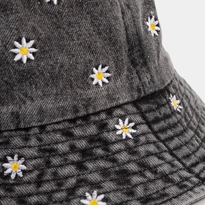 Close-up of small daisy embroidery and stitching on dark grey denim bucket hat