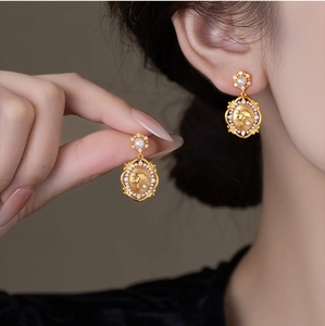 Detail of vintage gold-plated drop earring with pearl stud and ginkgo leaf relief design