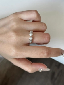 Detailed macro view of S925 silver twist ring with white pearls and zircon accents