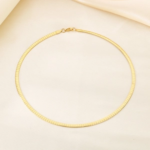 Detailed view of golden herringbone flat snake chain on elegant silk fabric