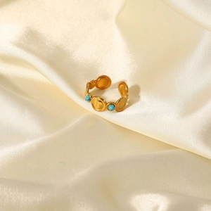 Detail of adjustable gold ring with turquoise stones on elegant beige silk fabric