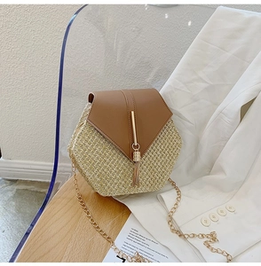 Detail of hexagonal straw crossbody bag with brown leather flap and gold tassel fringe