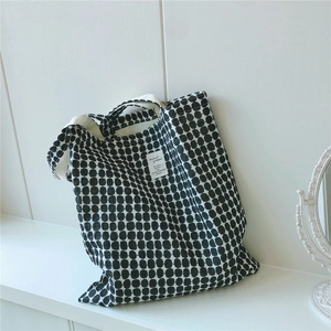 Detail of minimalist black and white polka dot canvas tote bag with woven strap