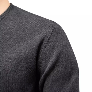 Gros plan du pull en tricot gris foncé à col rond mettant l'accent sur les coutures
