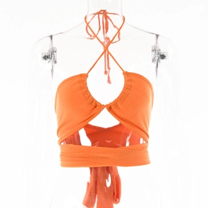 Détail du haut orange à licou avec taille croisée et découpes sur un mannequin transparent