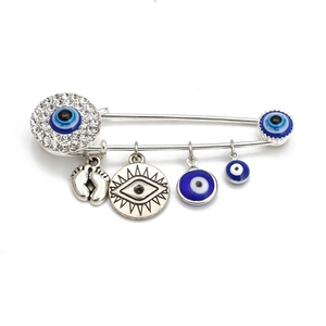 Detailed view of silver evil eye brooch with hanging charms and sparkling rhinestones