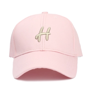 Détail d'une casquette rose avec lettre H brodée en argent et œillets de ventilation
