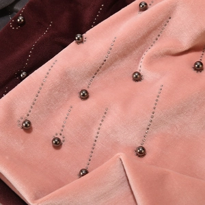 Detail of velvet fabric with silver studs and dark grey pearl embellishments on a warm hat